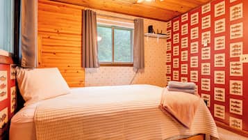 A wooden room with a bed, a window, and a wall with fish illustrations.