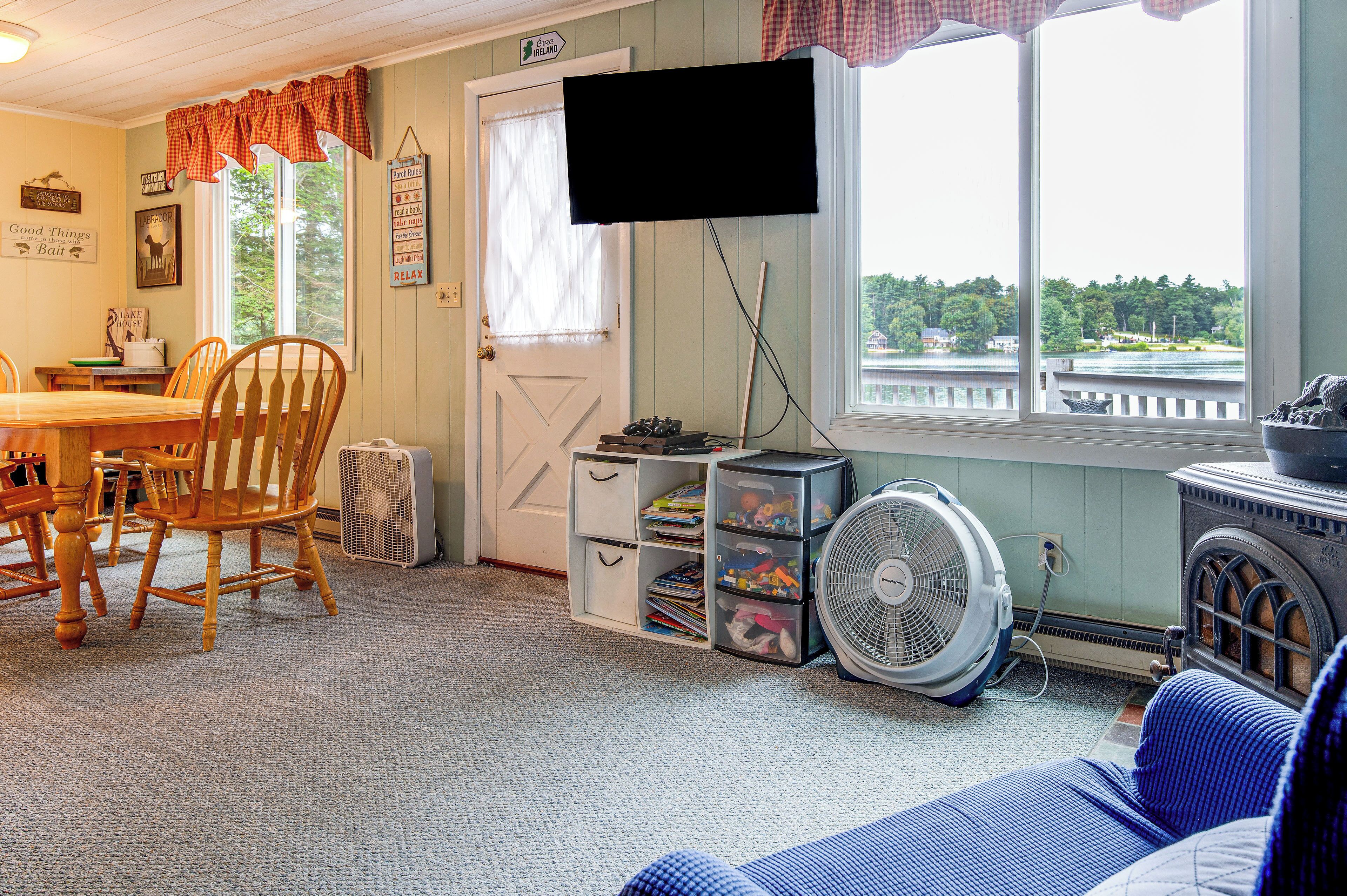A cozy room with a dining table, chairs, a television, and a view of a lake.
