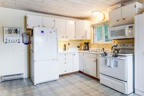 A kitchen with white cabinets, a refrigerator, a microwave, and a stove.