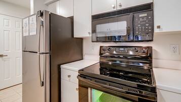 A kitchen with stainless steel appliances, including a refrigerator, microwave, and oven.