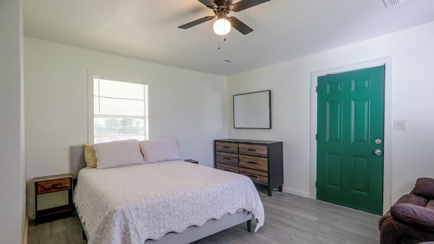 A bedroom with a bed, a dresser, a green door, and a ceiling fan. - Tailgate Ready! 3 Mi to Ole Miss & the Square (Oxford)