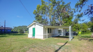 A small white building with a green door, a covered porch, and a speed hump sign in the background. - Tailgate Ready! 3 Mi to Ole Miss & the Square (Oxford)