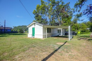 A small white building with a green door, a covered porch, and a speed hump sign in the background.