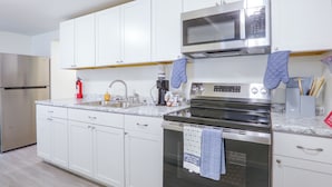 A modern kitchen with white cabinets, stainless steel appliances, and a marble countertop. - Tailgate Ready! 3 Mi to Ole Miss & the Square (Oxford)