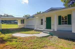 A single-story house with a covered porch, a green door, and a small front yard.
