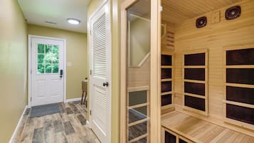 Pasillo que conduce a un cuarto de sauna con techo de madera y una puerta con ventana.