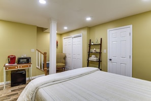 A bedroom with a bed, a desk with a coffee maker, a chair, a shelf with towels, and a door. - Private Sauna! Studio in Harpers Ferry (Harpers Ferry)