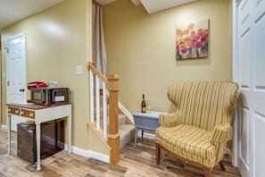 A living room with a striped armchair, a small table with a bottle and glass, a microwave, and a door. - Private Sauna! Studio in Harpers Ferry (Harpers Ferry)
