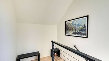 A modern interior with a wooden floor, a black bench, and a painting on the wall.