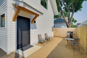 A house with a dark front door, a wooden porch, a barbecue grill, and outdoor seating. - 1 Mi to UM Campus! Newly Built Apt w/ Side Yard (Missoula)