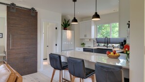 A modern kitchen with a large island, pendant lights, and a sliding barn door.