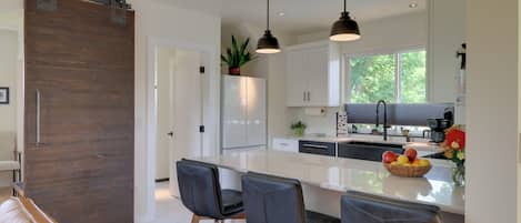 Una cocina moderna con una isla grande, luces colgantes y una puerta corrediza estilo granero.
