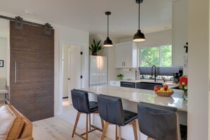 Une cuisine moderne dotée d’un grand îlot central, de luminaires suspendus et d’une porte coulissante de style rustique.