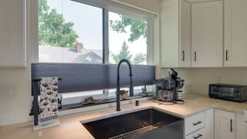 A kitchen with a large window, a sink, a coffee maker, and a toaster.