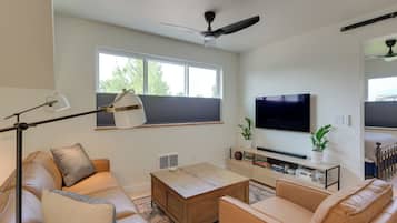 A modern living room with a sofa, coffee table, TV, and a ceiling fan.