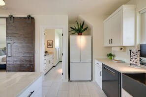 Une cuisine moderne avec des armoires blanches, un r éfrigérateur encastré et un mur d’accent en bois.