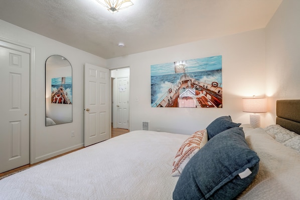 Un dormitorio con una cama grande, un cuadro de un barco en la pared y un ventilador de techo.