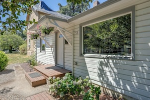 A house with a porch, a covered entryway, and a window with a view of greenery.