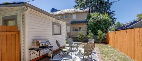 A wooden deck with outdoor furniture, a grill, and a small shed.
