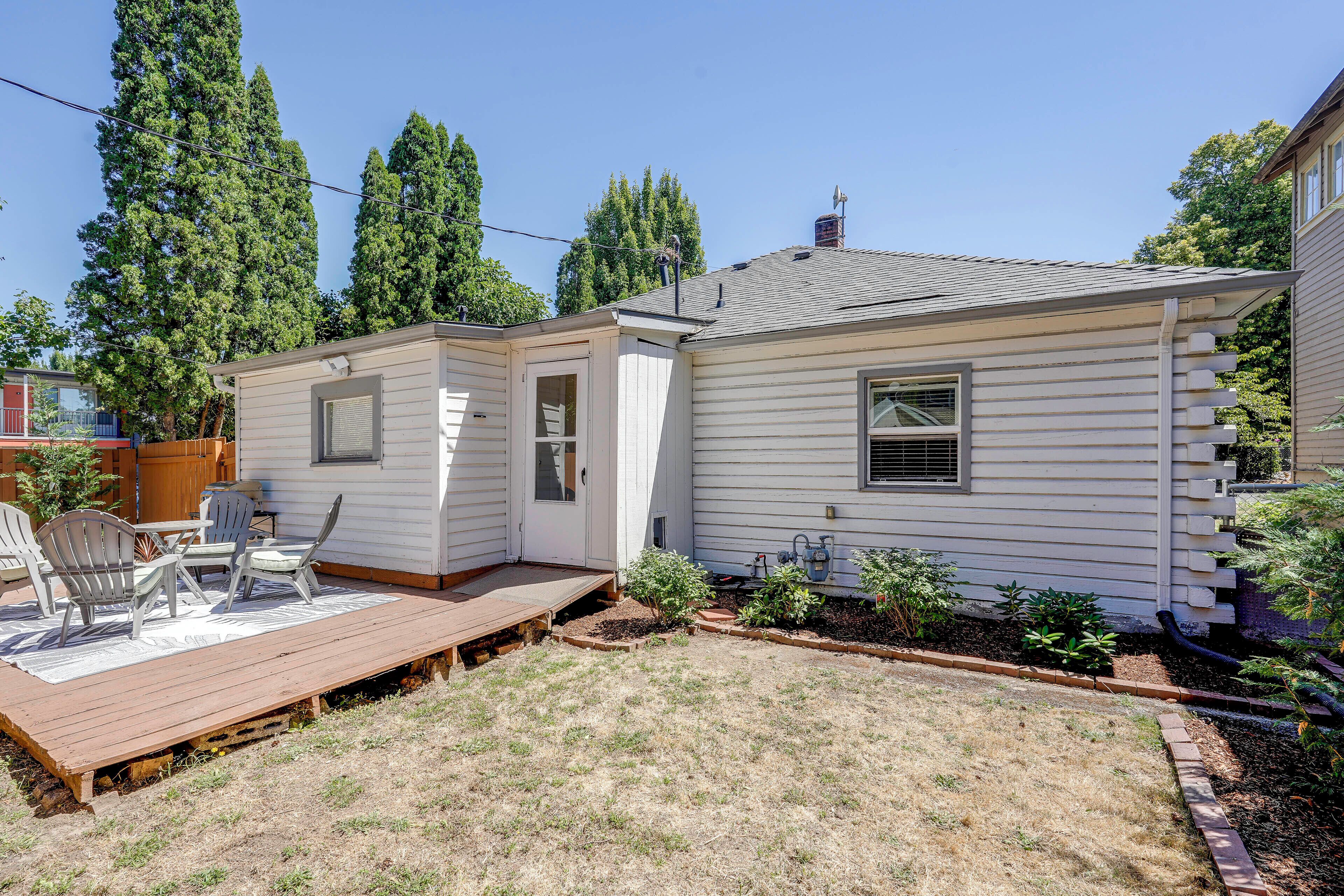 A single-story house with a deck, a small porch, and a garden area.