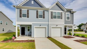 A two-story residential building with a garage, a covered entryway, and a well-maintained lawn.
