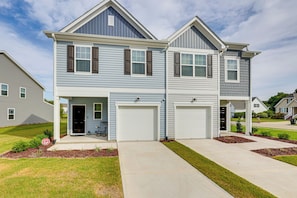 A two-story residential building with a garage, a covered entryway, and a well-maintained lawn.