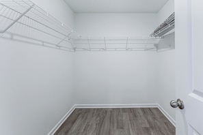 A small, enclosed storage space with a metal shelving unit and a wooden floor. - 2 Townhome Retreat Sleeps 12 40 Min to Raleigh (Wilson)