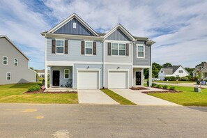 A two-story residential building with a central garage door, a small porch area, and a well-maintained lawn. - 2 Townhome Retreat Sleeps 12 40 Min to Raleigh (Wilson)