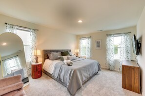 A bedroom with a large bed, a wooden nightstand, a mirror, a dresser, and a television.