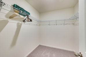 A corner of a room with a metal wire shelf holding various items, a carpeted floor, and a door with a silver handle.