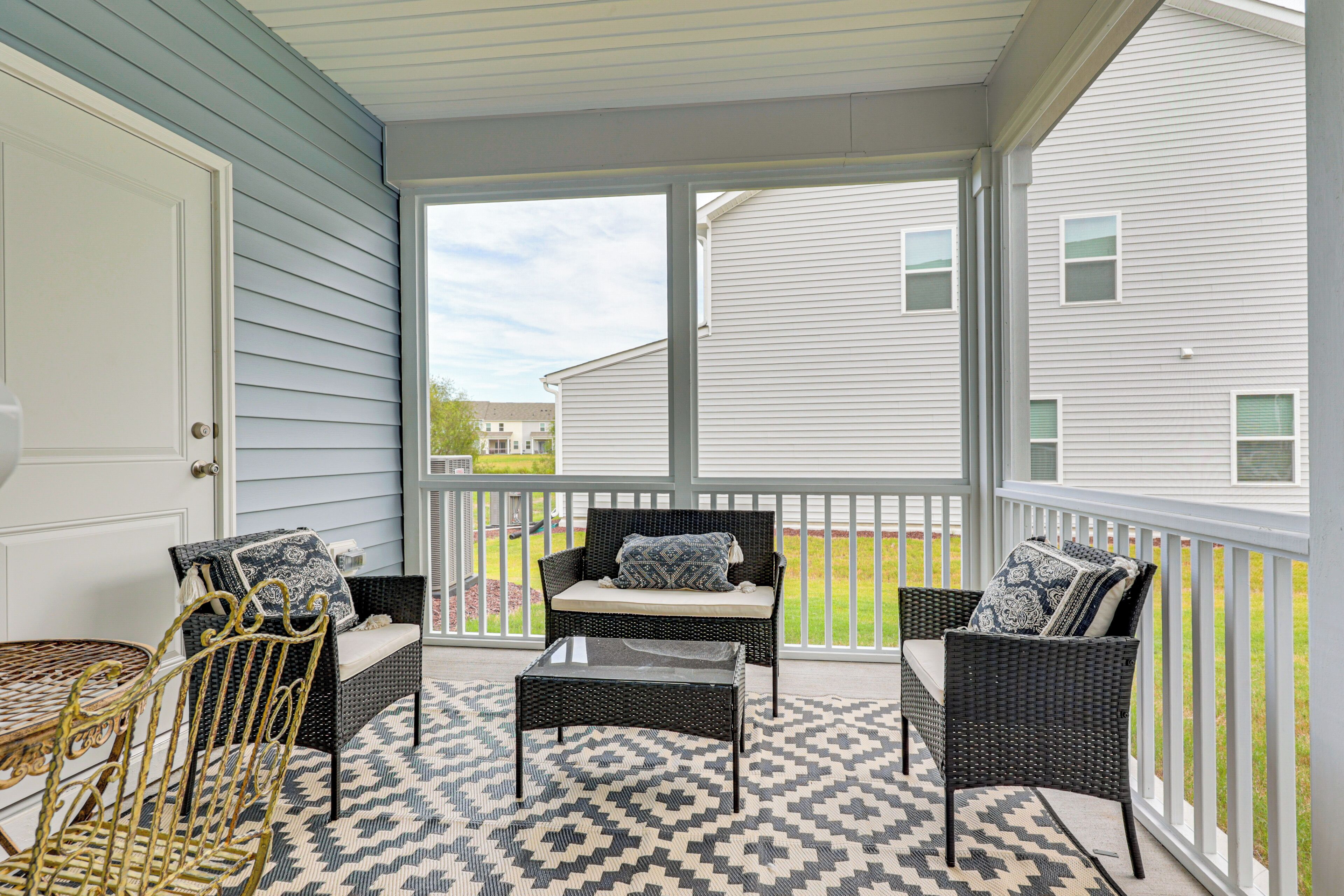 A covered porch with wicker furniture, a patterned rug, and a view of a residential area.