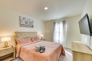 A bedroom with a bed, nightstands, a TV, and a painting on the wall.