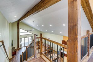 Ein großzügiger Innenraum mit hoher Decke, Holzbalken, einer Essecke und einer Treppe.
