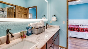 A bathroom with a large mirror, a sink, a towel rack, and a basket of toiletries. - Mtn-view Deck! Remote South Park Retreat (Hartsel)