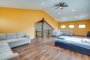 Ein geräumiges Zimmer mit schrägen Wänden, einem Deckenventilator und einem großen Fenster.
