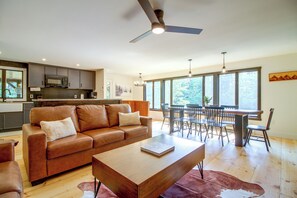 A modern kitchen with dark cabinets, a microwave, and a dining area with a wooden table and chairs.
