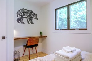 Ein Schlafzimmer mit Bett, einem Sessel, einem Fenster und einer Wanddekoration.