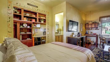 A hotel room with a bed, a desk, a kitchenette, and a bathroom.