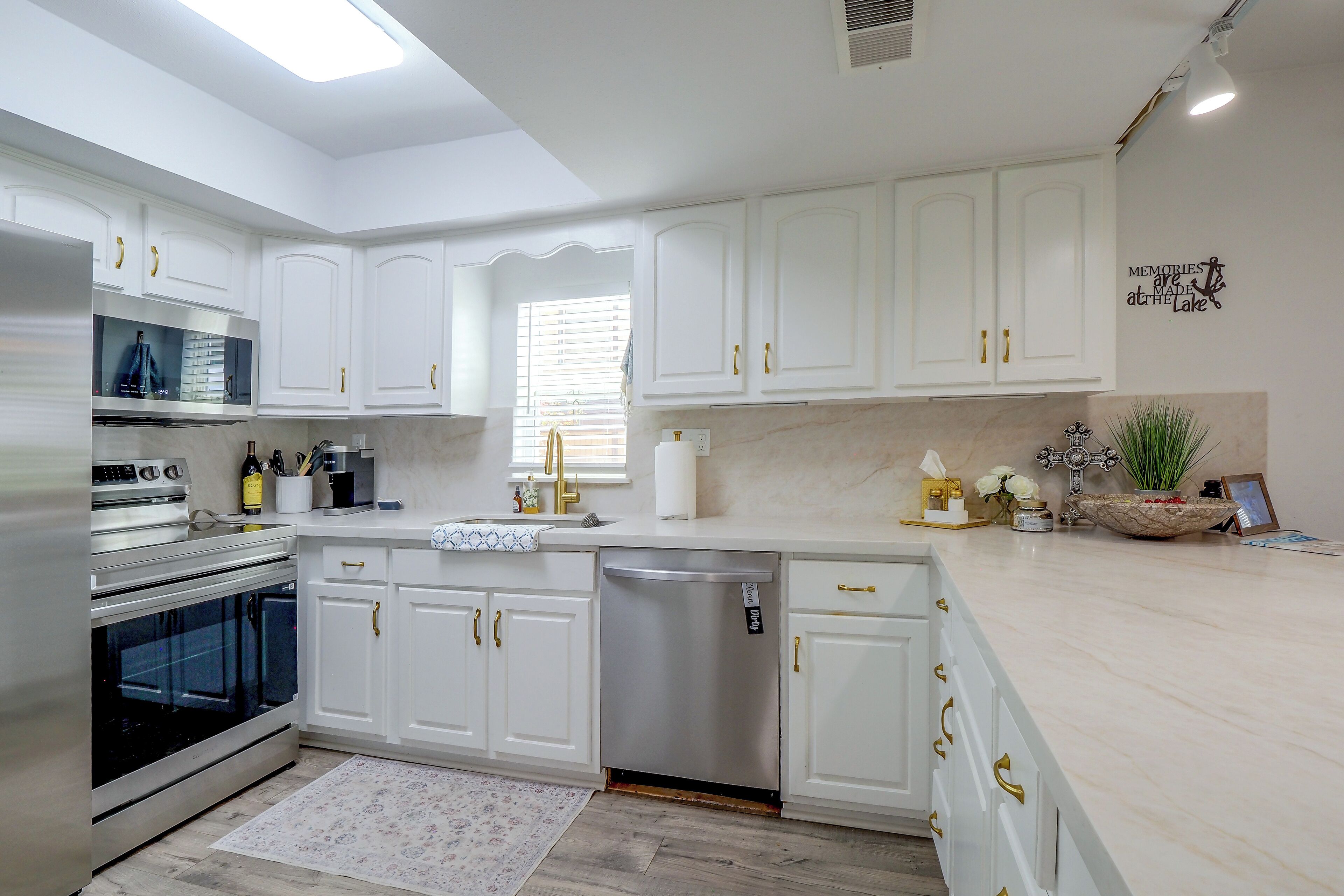 A modern kitchen with white cabinetry, stainless steel appliances, and a marble countertop.