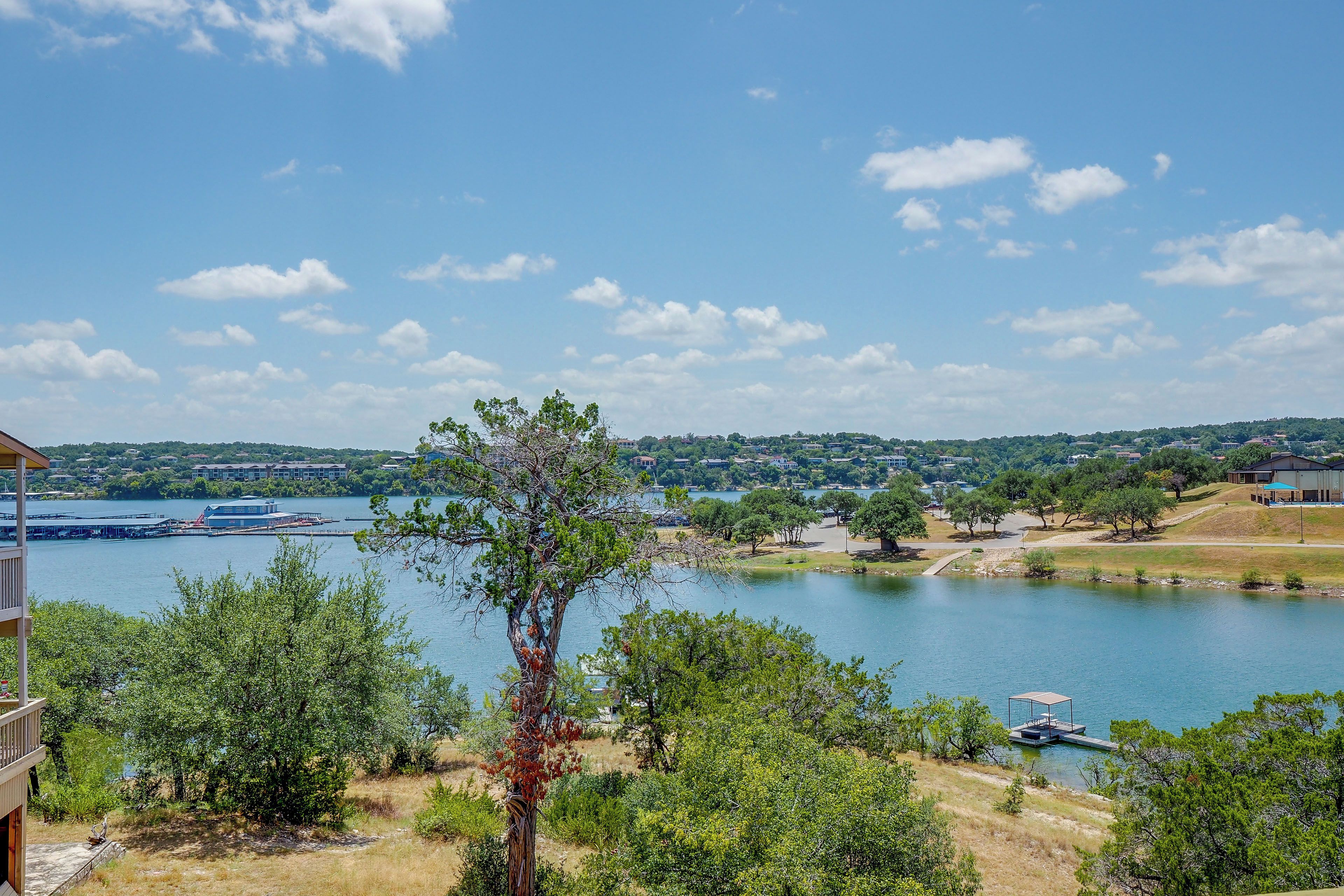 A lakeside view with a dock, trees, and a building in the background.