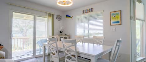 A dining area with a white table and chairs, a ceiling fan, and a view through the glass doors.