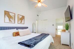 Ein Schlafzimmer mit Bett, Deckenventilator, Fernseher und Bildern an der Wand.