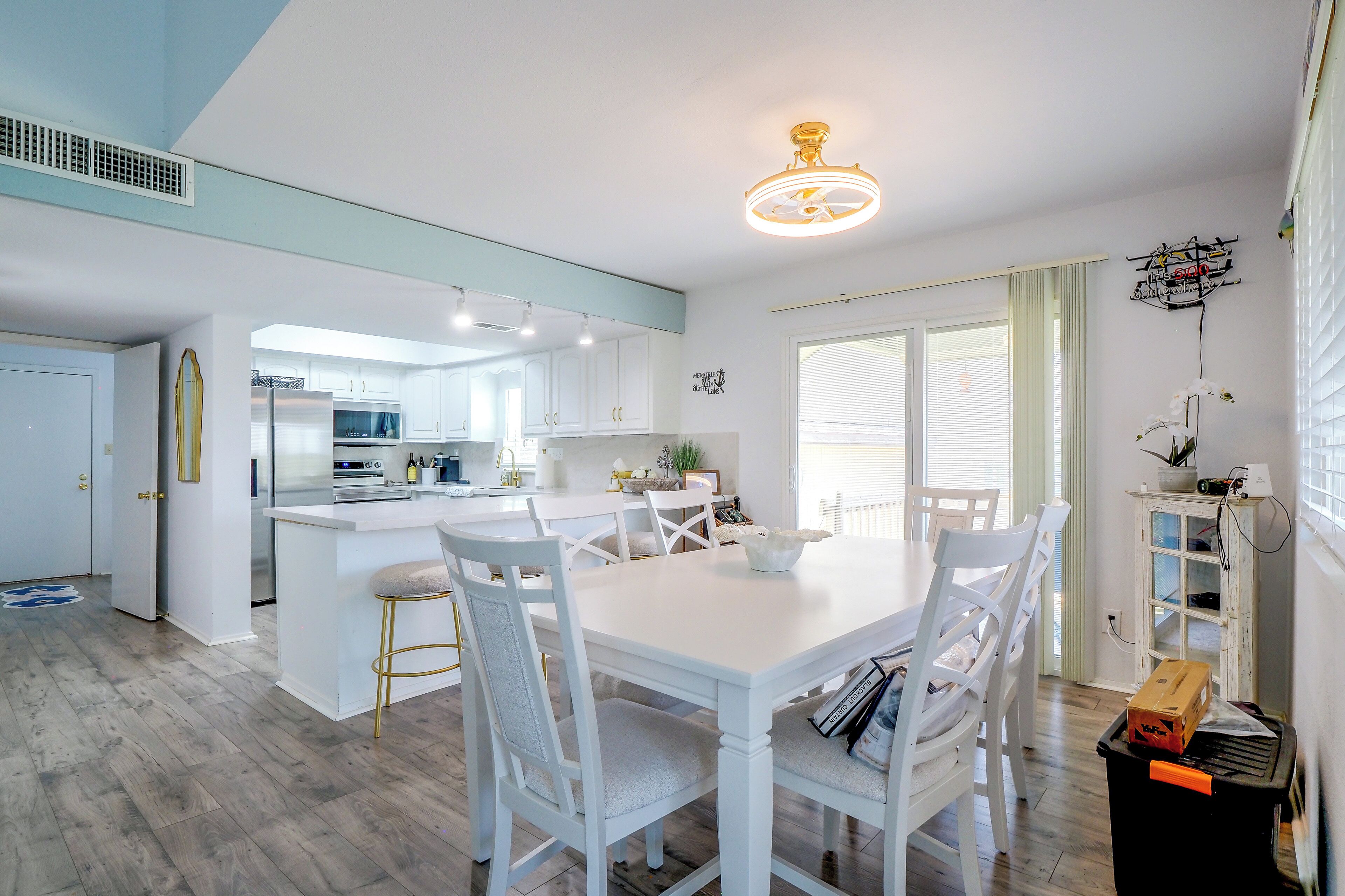 A modern kitchen with white cabinetry, a central island, and a dining area with white chairs and a table.