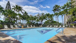 A swimming pool with lounge chairs and palm trees in the background. - 1 Mi to Makaha Beach: 10th-floor Condo w/ Views (Waianae)