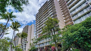 A high-rise residential building with multiple balconies, surrounded by lush greenery and palm trees. - 1 Mi to Makaha Beach: 10th-floor Condo w/ Views (Waianae)