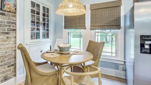 A dining area with wicker chairs, a round table, and a hanging light fixture. - Walk to Gulfport Beach! Quiet Home w/ Yard (Gulfport)