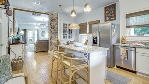 A modern kitchen with a central island, bar stools, a refrigerator, and a dining area with a view. - Walk to Gulfport Beach! Quiet Home w/ Yard (Gulfport)