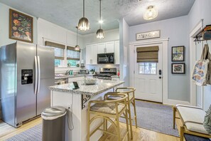 A modern kitchen with stainless steel appliances, a central island, and a dining area with wicker chairs. - Walk to Gulfport Beach! Quiet Home w/ Yard (Gulfport)