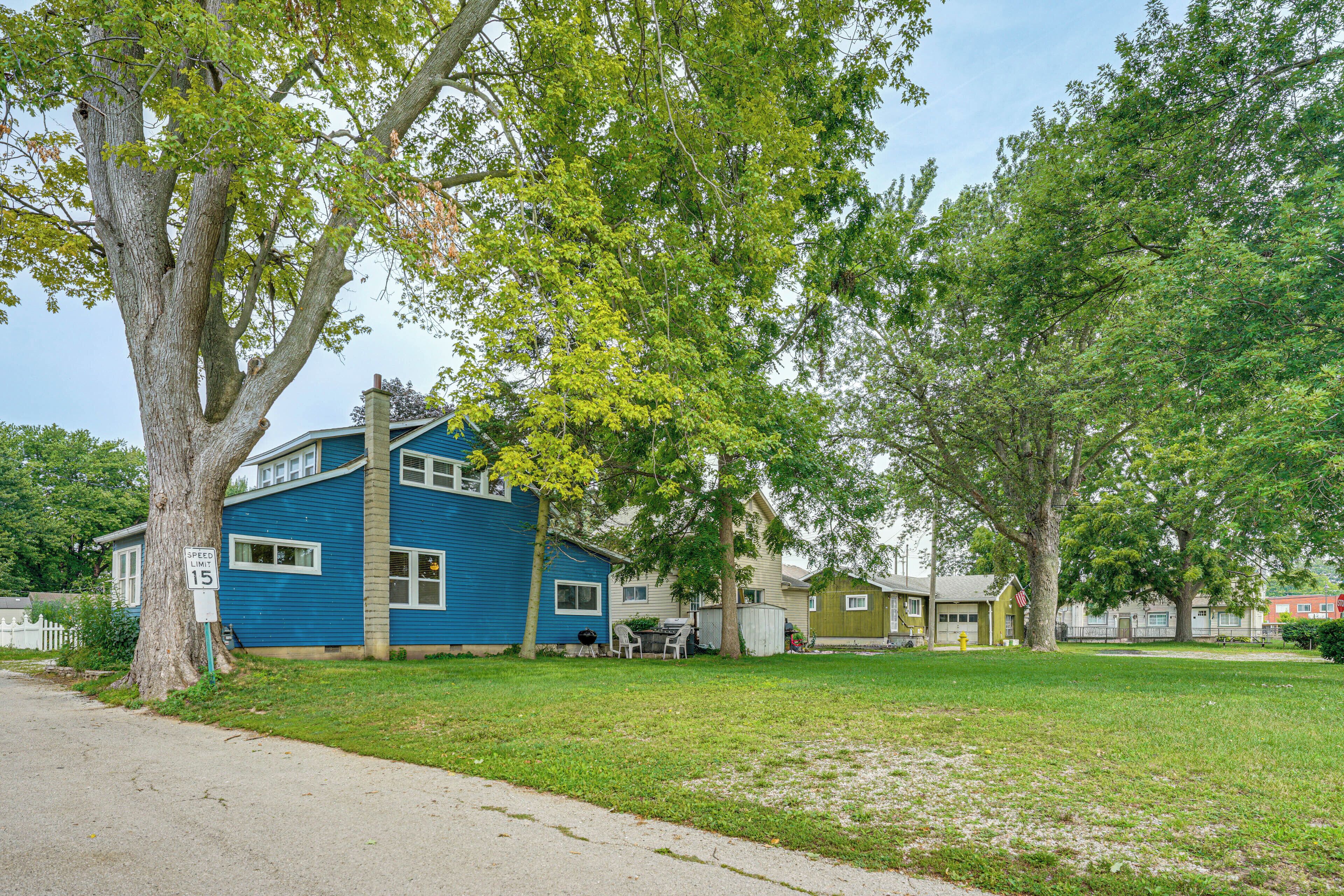 Un quartier résidentiel avec une maison bleue, une clôture blanche et une pelouse verdoyante.