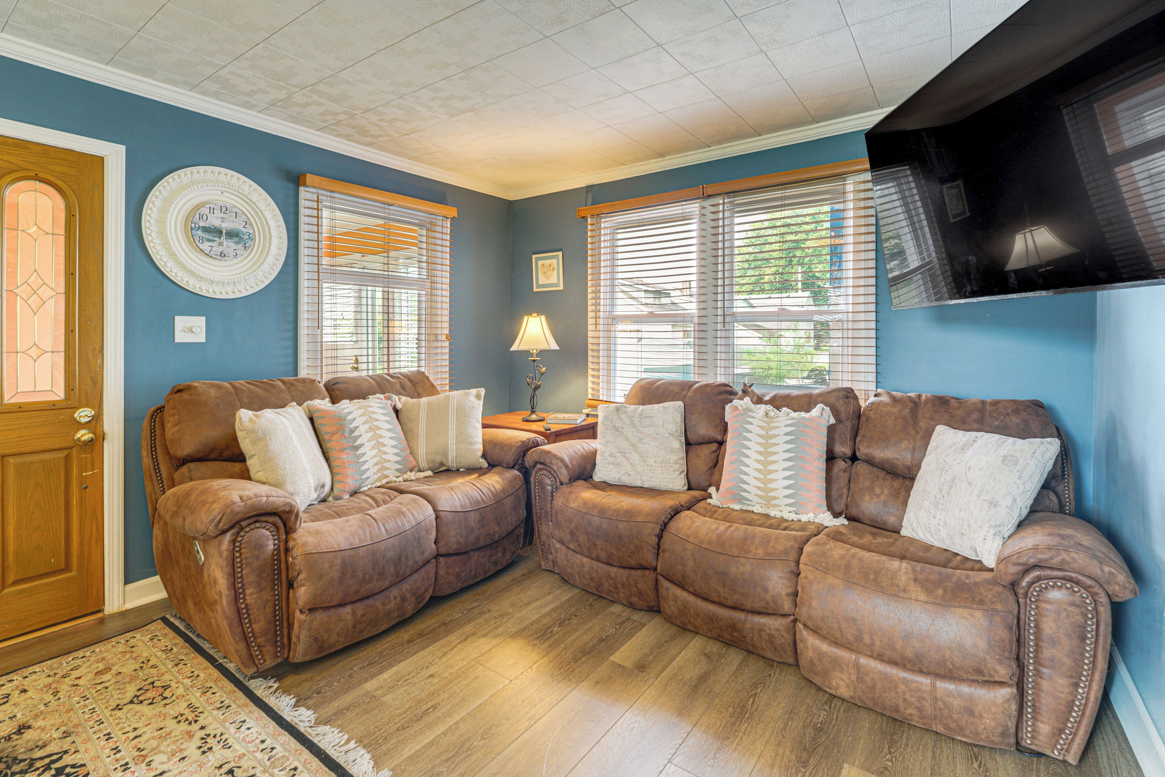 A living room with two brown leather sofas, a wooden door, and a patterned rug.